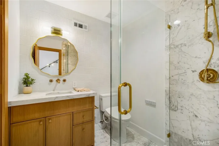 Downstairs designer bath (finished in Calacatta Dolomiti) with door to 1st floor bedroom and guest access door through hallway  | 305 Robinhood Ln., Eastside Costa Mesa 92627