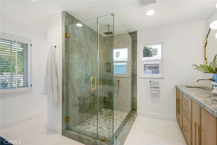 Spa-caliber primary bath with frameless glass shower in book-matched marble | 305 Robinhood Ln., Eastside Costa Mesa 92627