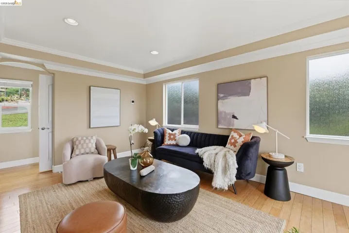 Bright living area featuring wood-finish flooring, recessed lighting, crown molding, and multiple windows
