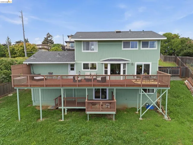 Expansive multi-level wood deck with wood railings, offering direct access to the interior via a sliding glass door and a standard entry door