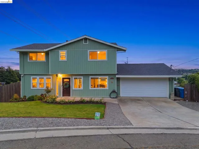 Two-story residence featuring a two-car garage, concrete driveway, and a front lawn with landscaping