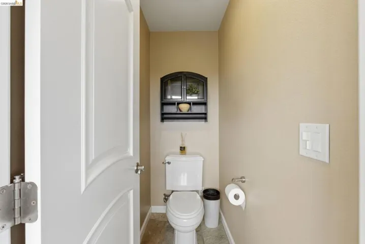 Powder room featuring a white two-piece toilet, beige wall paint, and light-colored floor tiles