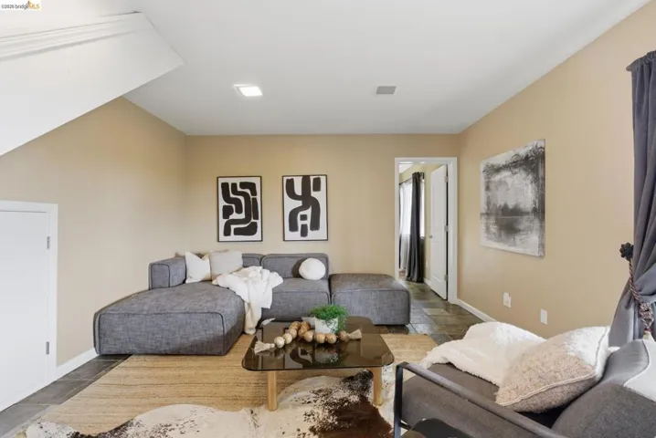 Spacious room featuring neutral wall tones, recessed lighting, and dark tile flooring
