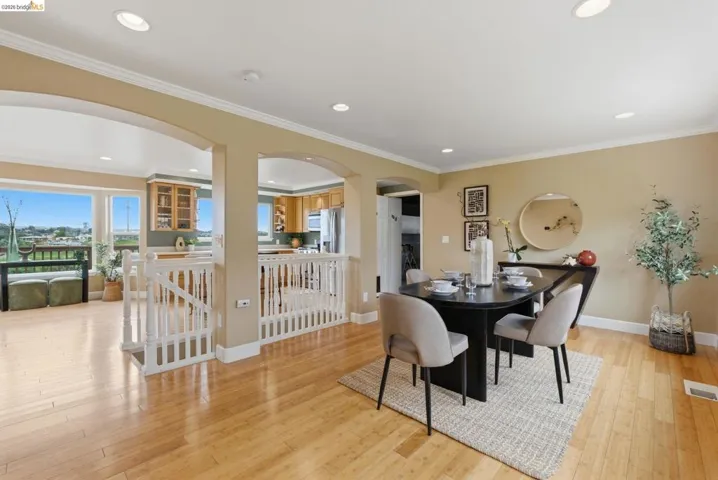 Bright dining area featuring wood-finish flooring, recessed lighting, and crown molding