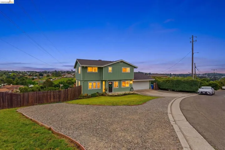 Two-story green siding home with a dark roof and a two-car garage