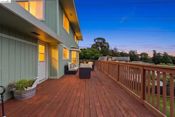 Expansive wood-finish deck with a wood-finish railing and light green siding exterior