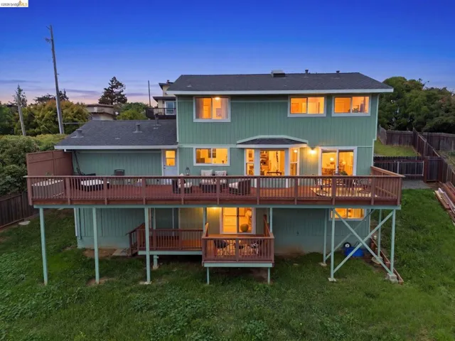 Multi-level residence featuring a spacious upper deck with wood railing, a lower-level deck, and wood-paneled siding