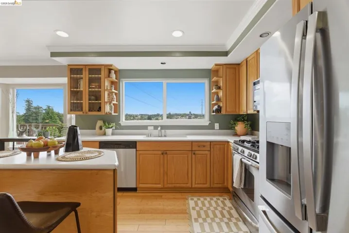 Kitchen featuring light wood cabinetry, recessed lighting, stainless steel appliances, and a central island with a white countertop