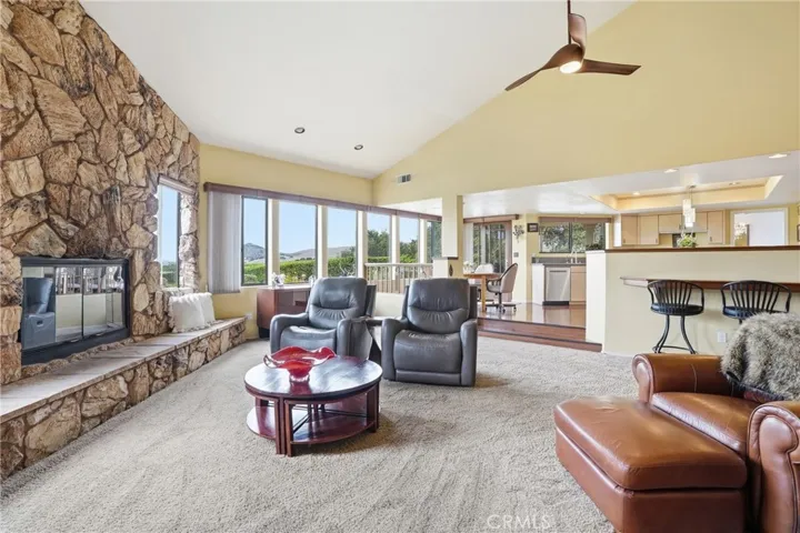 Family room with floor-to-ceiling stone fireplace adjoins open kitchen and dining bay--all with exquisite views