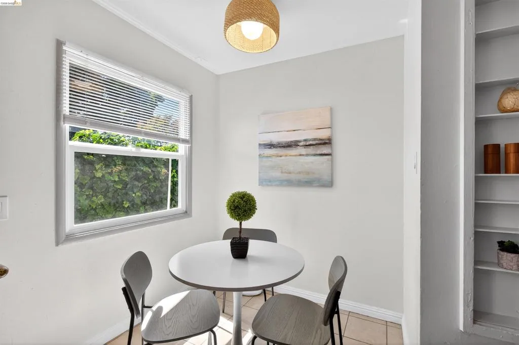 Compact dining area featuring a window with white blinds, neutral wall paint, and built-in shelving