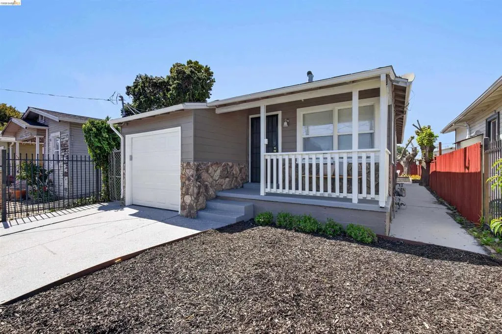 Exterior featuring a covered front porch with white railing, stone accents, horizontal siding, and an attached garage with a white door