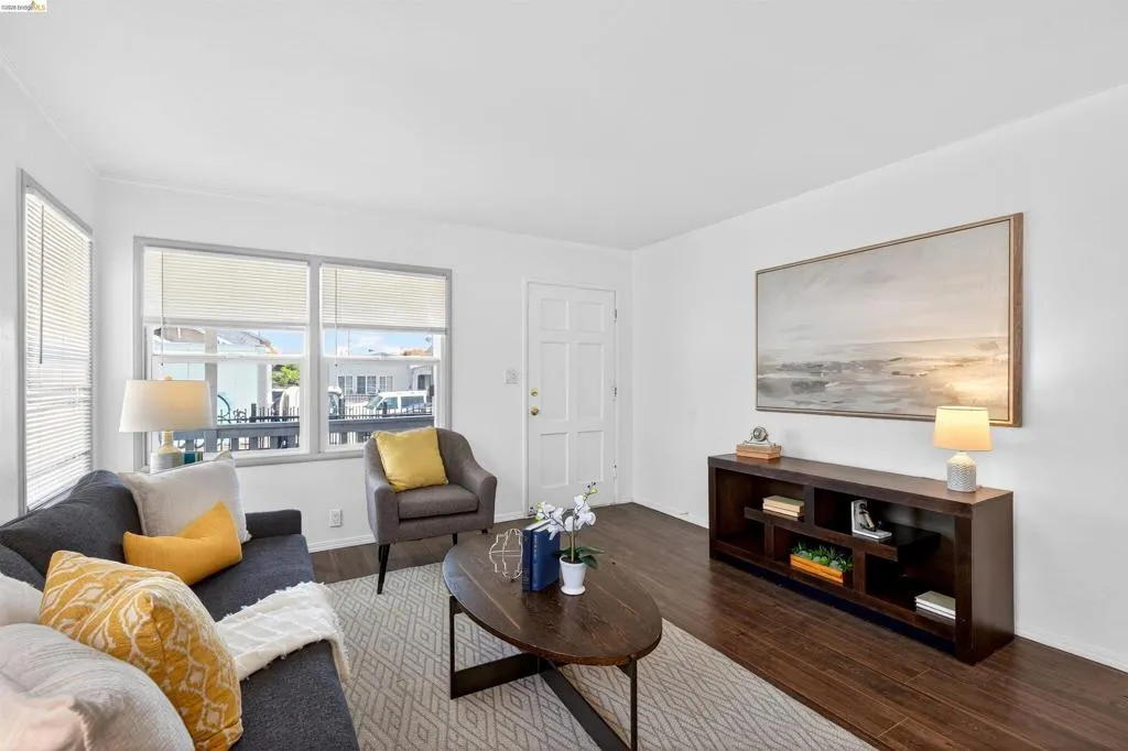 Living area featuring wood-finish flooring, white walls, and multiple windows with blinds