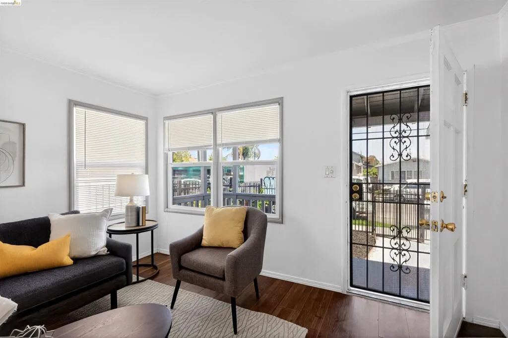 Interior space featuring wood-finish flooring, white walls, and bright windows with blinds