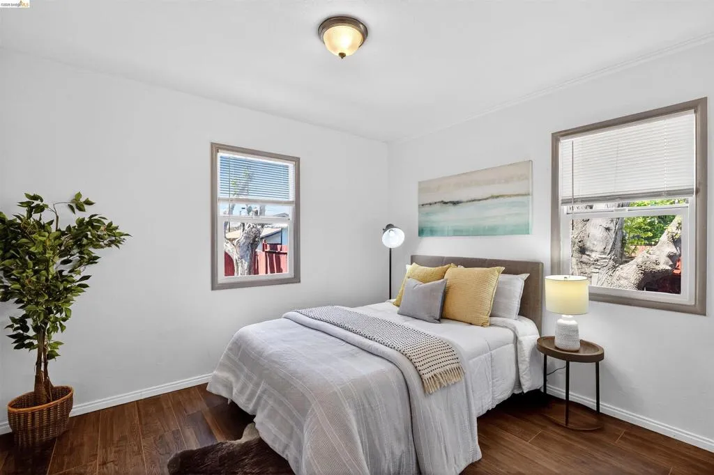 Spacious room featuring rich wood-finish flooring, white baseboards, and bright white walls