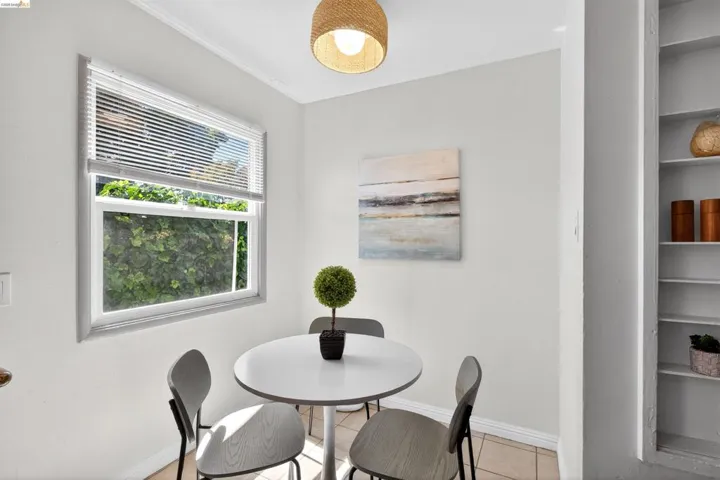 Compact dining area featuring a window with white blinds, neutral wall paint, and built-in shelving
