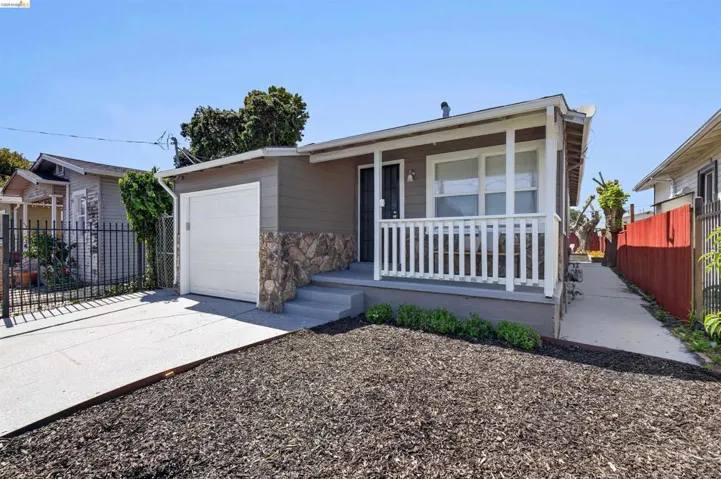 Exterior featuring a covered front porch with white railing, stone accents, horizontal siding, and an attached garage with a white door