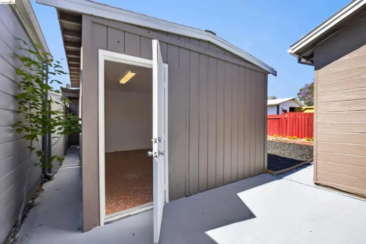 Detached utility structure featuring a light brown exterior, white trim, and a shed-style roof