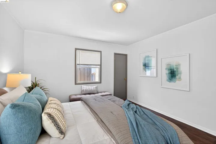 Bedroom featuring dark wood-finish flooring, white walls, and a window with blinds