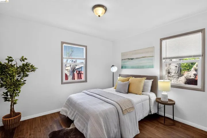 Spacious room featuring rich wood-finish flooring, white baseboards, and bright white walls