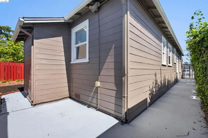 Side exterior featuring horizontal siding, white-framed windows, and concrete pathways