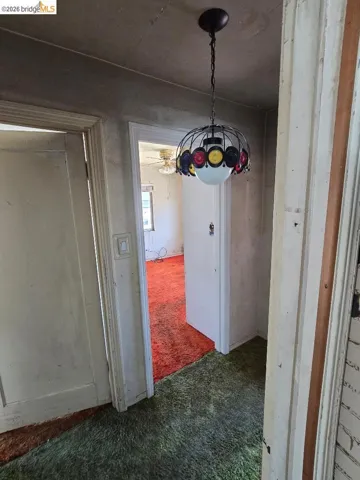 Entryway featuring a decorative ceiling light fixture with a globe diffuser, two doorways with white trim, and multi-color carpeting