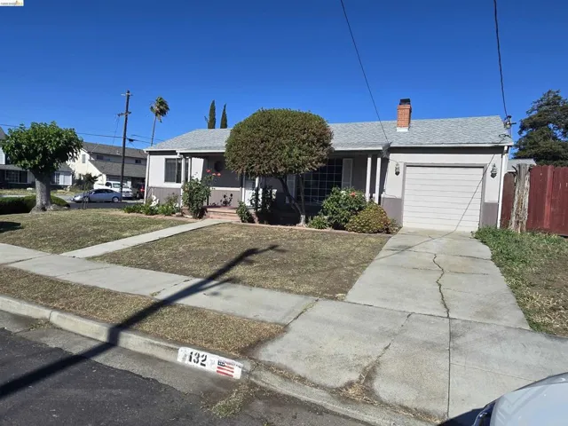 Single-story home featuring a gray stucco exterior with white trim, a front-facing garage with a paneled door, and a brick chimney