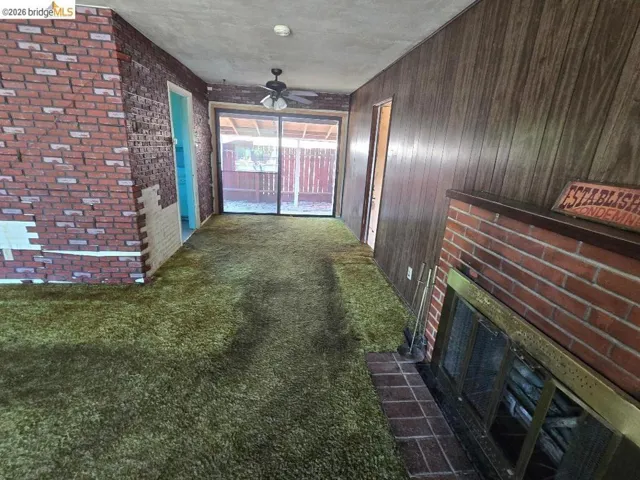 Interior space featuring green carpet flooring, wood-paneled walls, and a brick fireplace