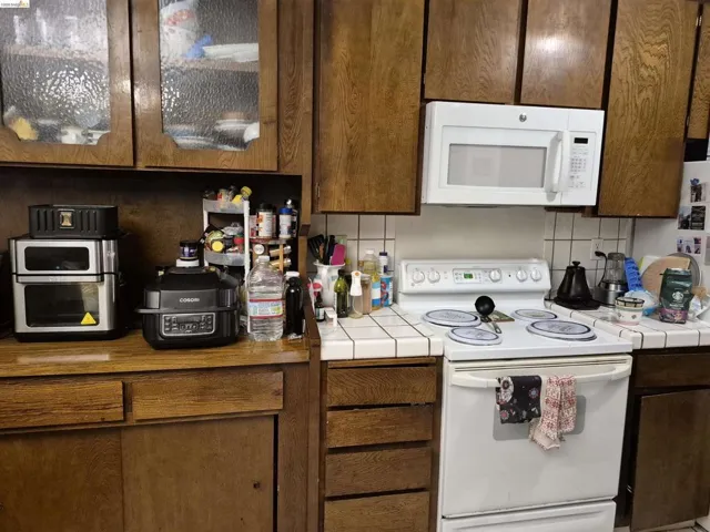 Kitchen featuring wood cabinetry, a white electric range, and a white over-the-range microwave