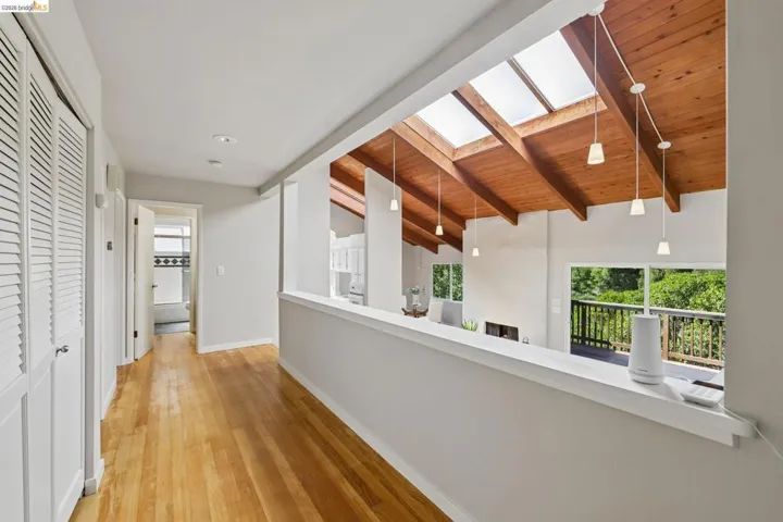 Hallway with wood-finish flooring and louvered bifold closet doors