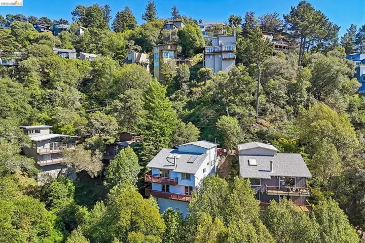Hillside residence featuring multiple levels, balconies, and a surrounding green landscape