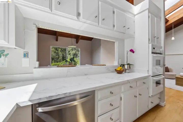 Kitchen with white cabinetry, stainless steel dishwasher, integrated wall oven, and white countertops