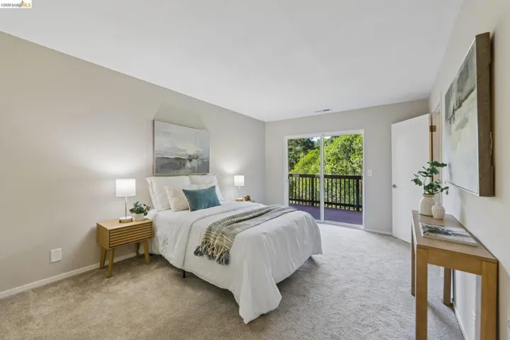 Carpeted room with a full-light sliding glass door opening to an outdoor deck featuring a dark wood railing