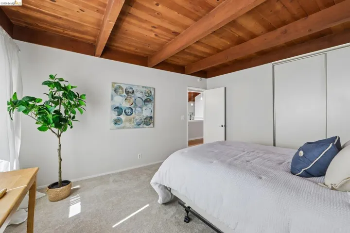 Vaulted wood-paneled ceiling with exposed beams, light gray walls, and light-toned carpeting