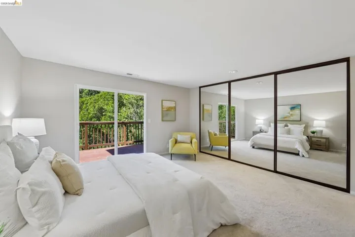 Bedroom featuring a full wall of mirrored closet doors, light neutral wall paint, and plush carpet flooring