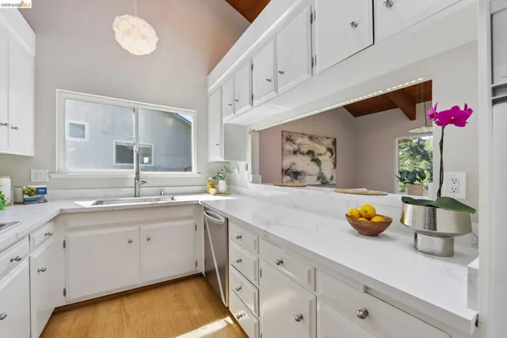 Kitchen featuring vaulted wood-paneled ceilings, white cabinetry with silver hardware, and white countertops