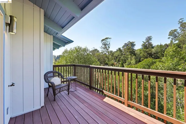 Spacious outdoor deck featuring wood-finish flooring, a sturdy wood railing, and a bronze wall sconce