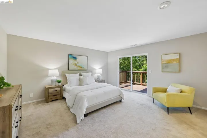 Carpeted bedroom featuring a sliding glass door to an outdoor deck, recessed ceiling lighting, and neutral wall tones