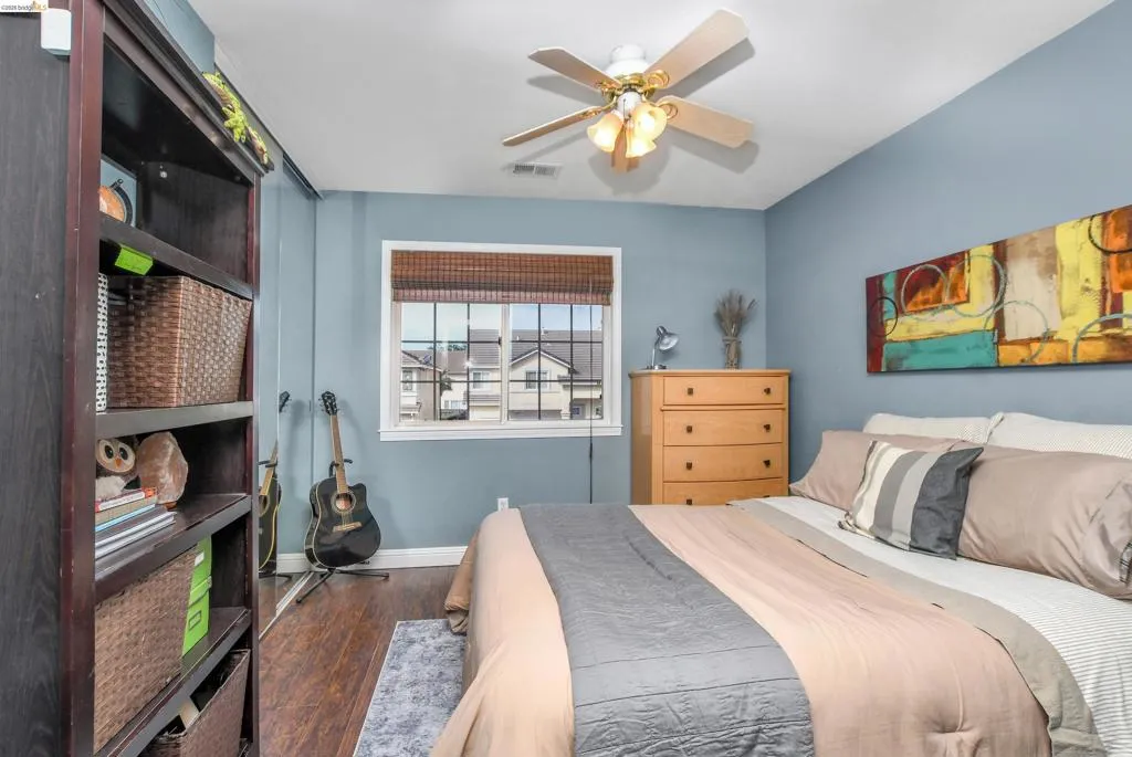 Hardwood-finish flooring featuring a window with grid patterns and a woven wood shade