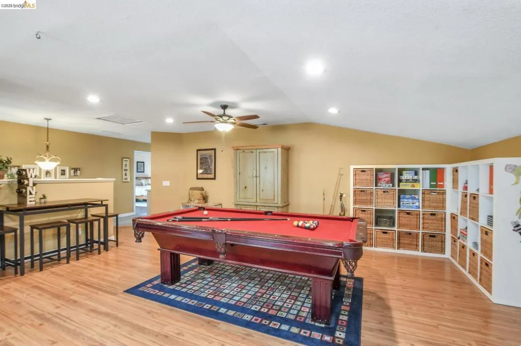 Spacious room featuring wood-finish flooring, recessed lighting, and a ceiling fan