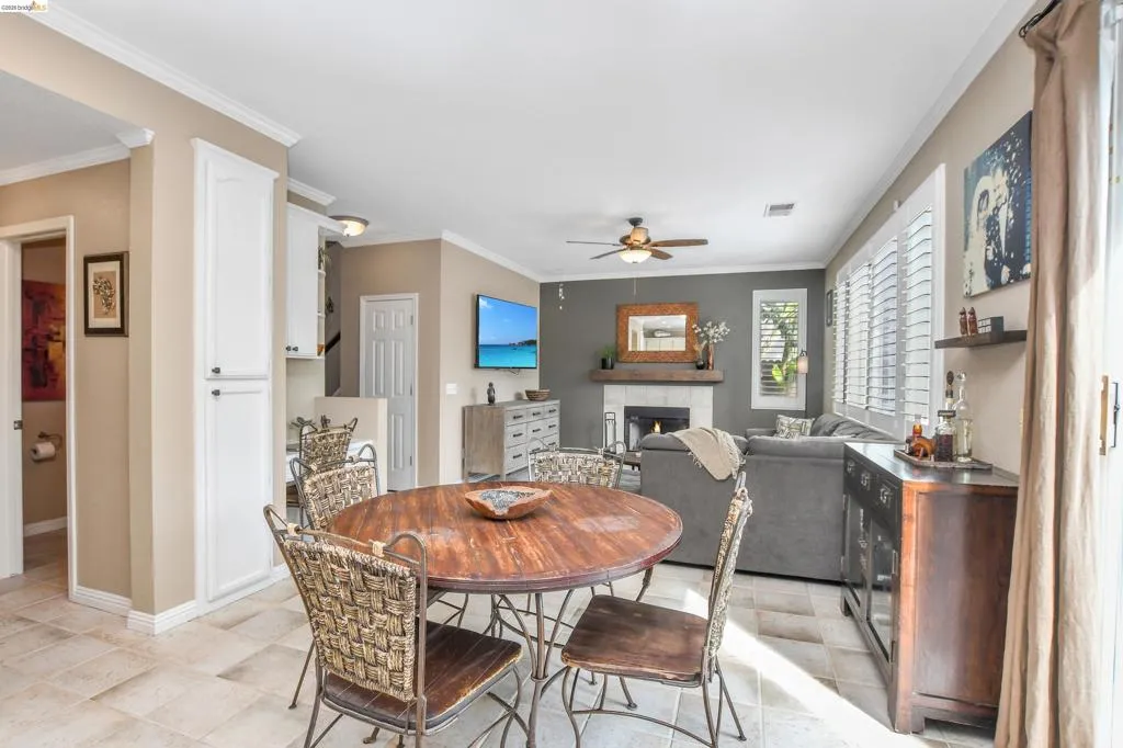 Open-concept living space with tile flooring throughout, featuring a fireplace with a stone surround and wooden mantel, and built-in white cabinetry