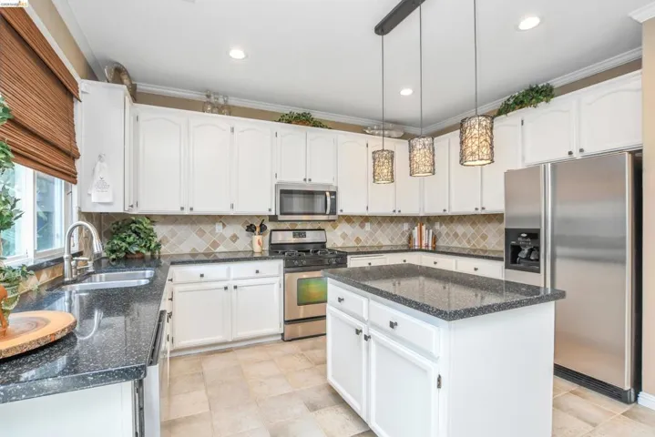 Kitchen featuring white cabinetry, dark speckled countertops, stainless steel appliances, a tiled backsplash, and recessed lighting