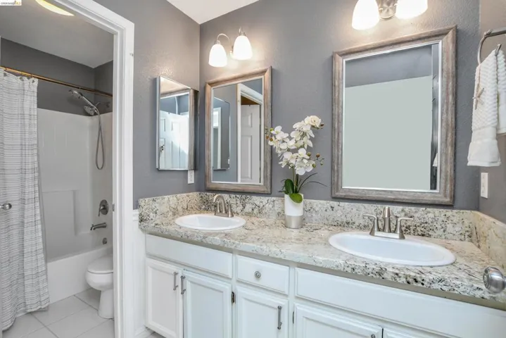 Dual vanity with undermount sinks, speckled countertop, and white cabinetry