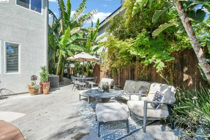 Paved outdoor patio space featuring mature tropical landscaping and a privacy fence
