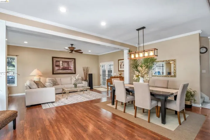 Open concept living and dining areas featuring wood-finish flooring, recessed lighting, crown molding, and a ceiling fan
