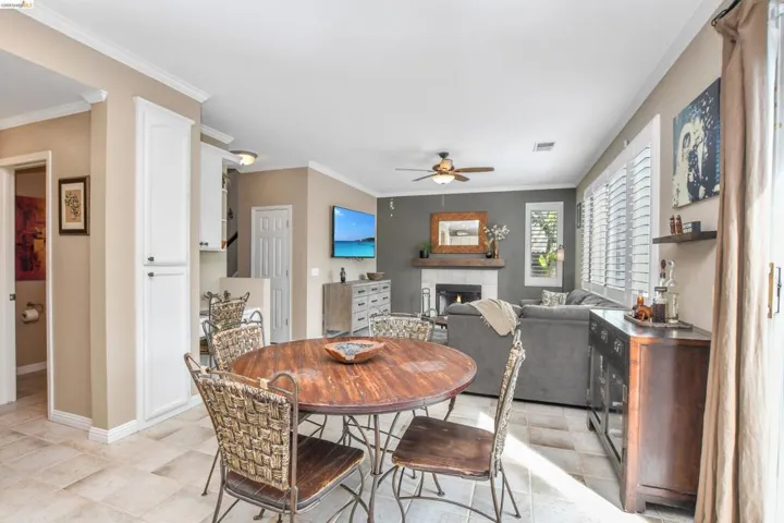 Open-concept living space with tile flooring throughout, featuring a fireplace with a stone surround and wooden mantel, and built-in white cabinetry