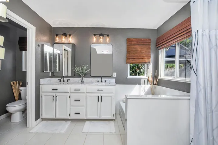 Dual vanity with white cabinetry, stone countertops, and matte black hardware