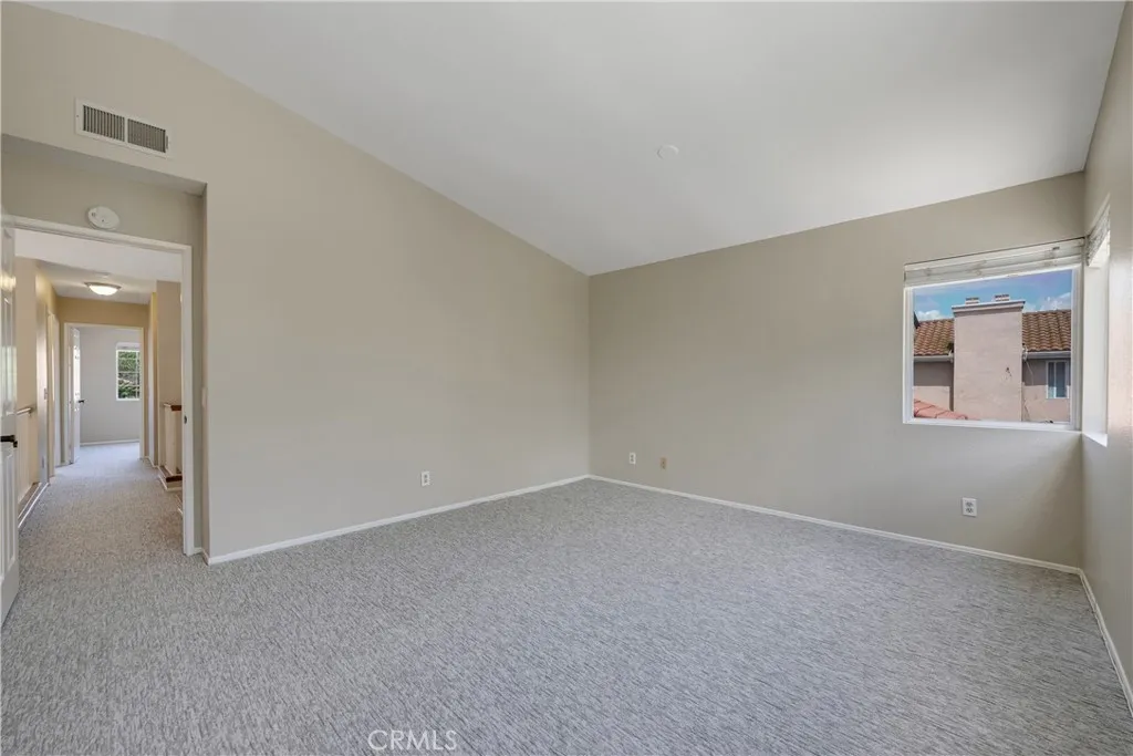 Primary bedroom at top of stairs has high cathedral ceiling.