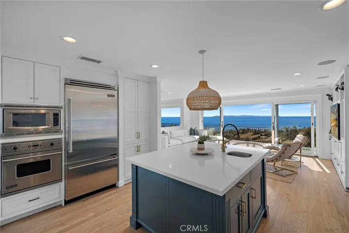 the chef’s kitchen features quartz countertops, custom cabinetry brass fixtures and hardware, designer lighting, top-of-the-line Viking appliances, and a large center island complete with prep sink, wine fridge, and breakfast bar seating.