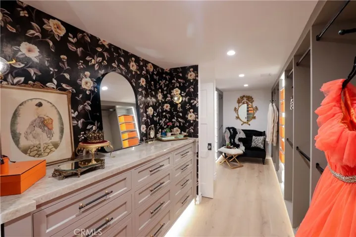 An exceptional dressing room style primary closet with extensive custom storage, a striking Onyx countertop and thoughtfully designed space for every wardrobe essential.
