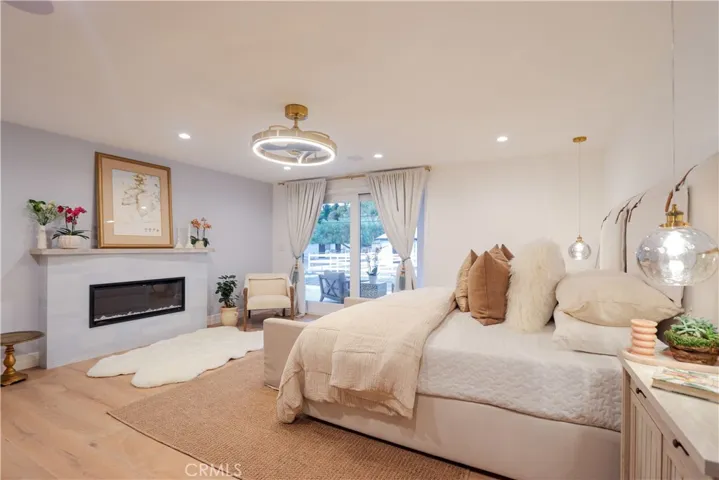 The luxurious primary suite is a private sanctuary featuring a fireplace, expansive proportions, and direct access to the oversized patio for seamless indoor-outdoor living.